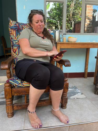 a woman sitting in a chair holding a cell phone at Meleji Studio House in Arusha