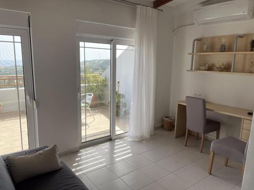 a living room with a table and a desk with a view at Sea View Loft in Koskinou