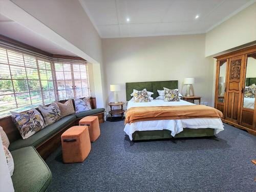 a large bedroom with a bed and a couch at Hydrangea Guest House in Nottingham Road