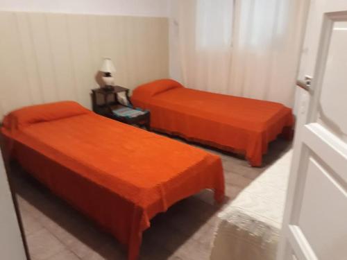2 camas naranjas en una habitación con silla en Casa céntrica en Mar del Plata