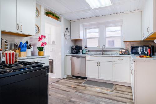 a kitchen with white cabinets and a black stove top oven at King Bed, Stocked Kitchen, Easy Driveway Parking, 2mi to Downtown & Coliseum in Fort Wayne