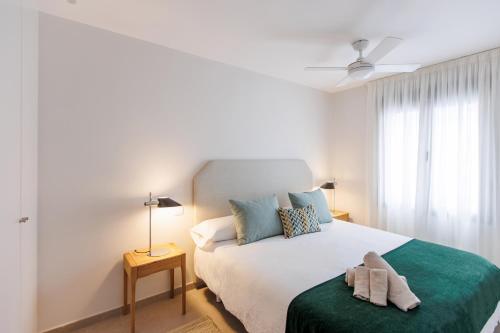a white bedroom with a bed with a green blanket at NEW Stylish 2 Bedroom Apt in Las Palmas de Gran Canaria