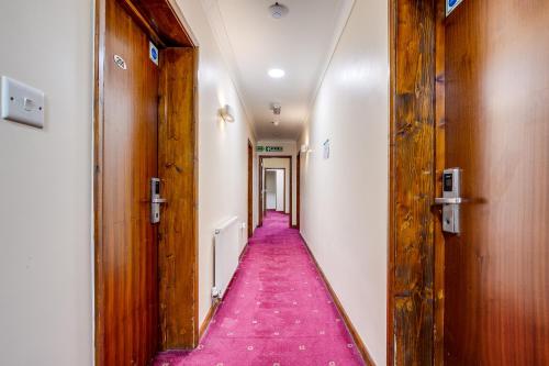 a corridor with a pink carpet in a hallway at London Star Hotel in London