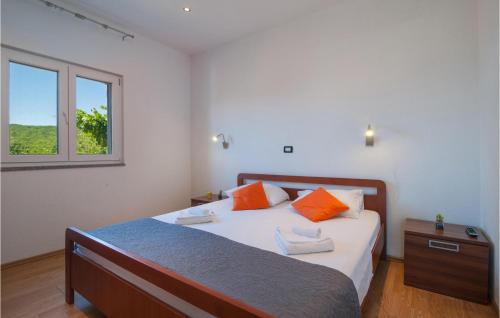a bedroom with a bed with orange pillows and a window at Nice Home In Slivno With Outdoor Swimming Pool in Slivno