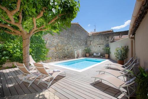 a pool with chairs and a tree next to a building at La Chasse au Bonheur in Rieux-Minervois