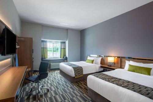 a hotel room with two beds and a flat screen tv at Microtel Inn & Suites by Wyndham Liberty NE Kansas City Area in Liberty