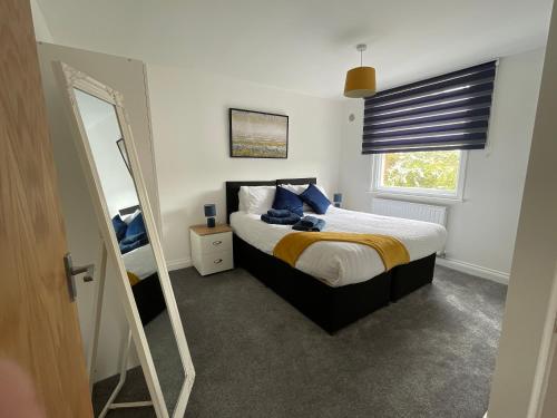 ein Schlafzimmer mit einem großen Bett und einem Spiegel in der Unterkunft Towerview Apartments Braintree in Braintree