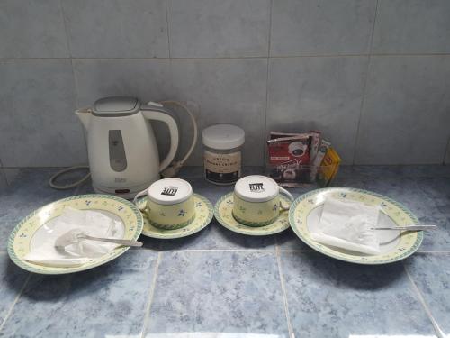 einen Tisch mit vier Tellern und einen Wasserkocher in der Unterkunft C4 homestay in Jakarta