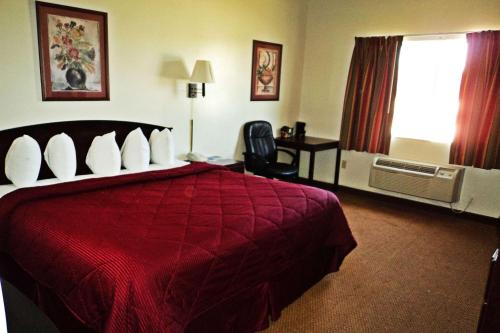 een hotelkamer met een rood bed en een televisie bij Travelodge by Wyndham Carlsbad NM in Carlsbad