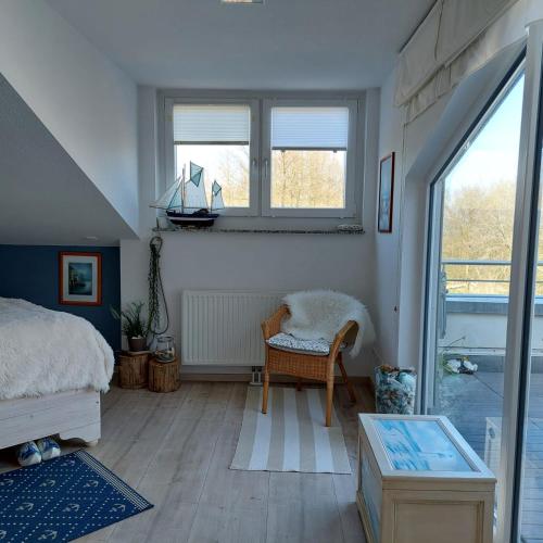 a bedroom with a bed and a chair and windows at Ferienwohnung Meeresrauschen in Graal-Müritz