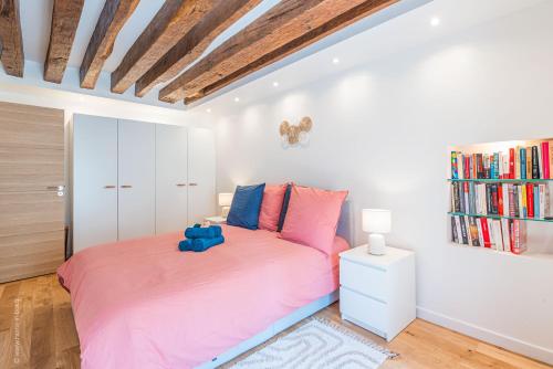 - une chambre avec un lit rose et une étagère à livres dans l'établissement Le Petit Rex, à Paris