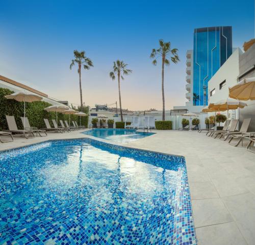 - une piscine bordée de chaises et de palmiers dans l'établissement Hotel RH Portocristo & Wellness, à Peñíscola