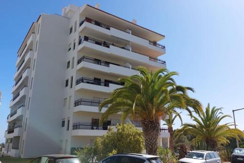 um edifício branco com palmeiras em frente em Fantastic Apartment in Praia do Vau em Portimão