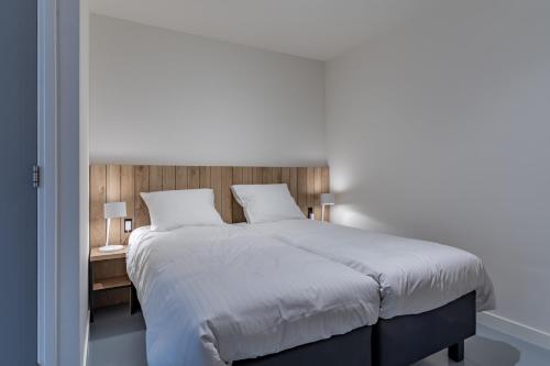 1 dormitorio con 1 cama blanca grande y mesita de noche en SneekermeerZicht, en Offingawier