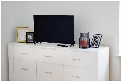 a white dresser with a tv on top of it at Color24 Apartament VI in Stalowa Wola