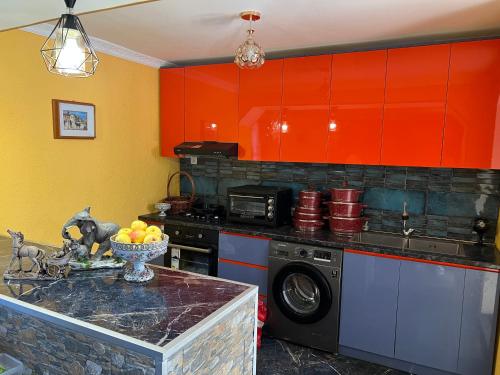 eine Küche mit orangefarbenen Schränken und einer Waschmaschine in der Unterkunft NIKATOLO - HOTEL GUESTHOUSE 