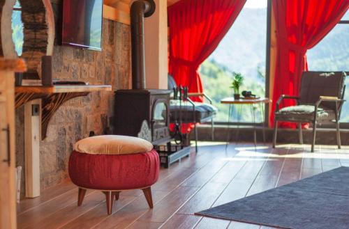 Çamlıhemşin的住宿－Dastavi Dağ Evleri，客厅配有燃木火炉和红色的搁脚凳