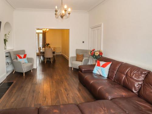 a living room with a brown leather couch and a dining room at 7 Lonsdale Terrace in Penrith
