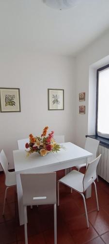 a white table with chairs and a vase of flowers on it at La Casa di Gigliola in Monticiano