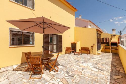 a patio with a table and chairs and an umbrella at Ninestories Baleal in Ferrel