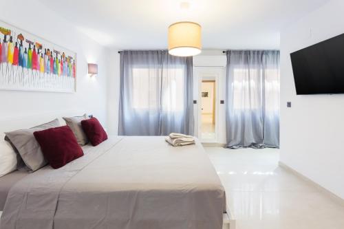 a white bedroom with a large bed and a flat screen tv at Lujoso cerca de playa in Jávea