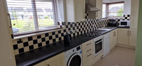 a kitchen with black and white tiles on the wall at Two Bedroom Self Catering Apt. The Hawthorn's. Sligo in Sligo