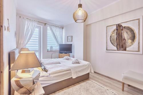 a bedroom with a bed with a lamp and a window at Chrobry by Baltic Home in Międzyzdroje