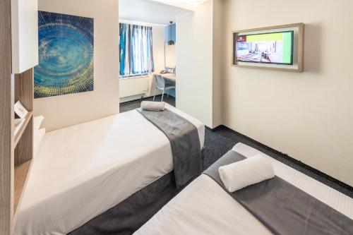 a hotel room with two beds and a tv at Road Lodge Isando in Germiston