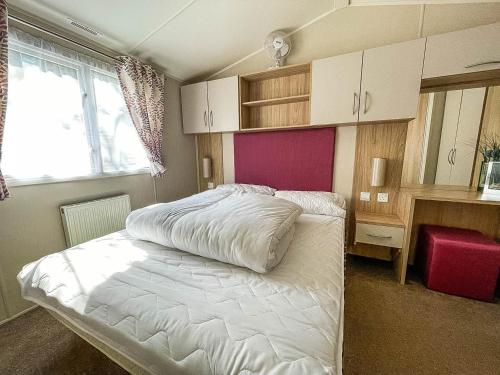 a bedroom with a bed and a desk and a window at Modern Caravan With Decking At Azure Seas Along The Suffolk Coast Ref 32065az in Lowestoft