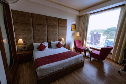 a hotel room with a bed and a large window at Hotel Millennium Inn, Prayagraj in Allahābād