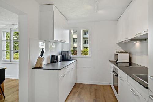 a white kitchen with white cabinets and appliances at Erlen Rooms in Luzern