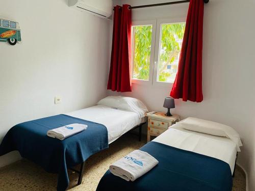 デニアにあるAlbaranas LOCDENIAのベッドルーム1室(ベッド2台付)、赤いカーテン付きの窓が備わります。