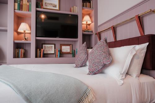 a bedroom with a white bed with pillows and a flat screen tv at The Sanctuary House Hotel in London