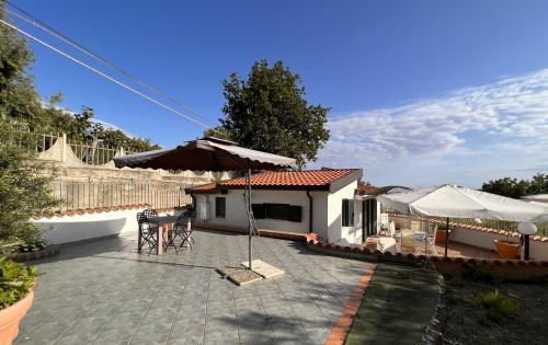 un patio con una sombrilla y una casa en Villa Gina, en Marina di Fuscaldo
