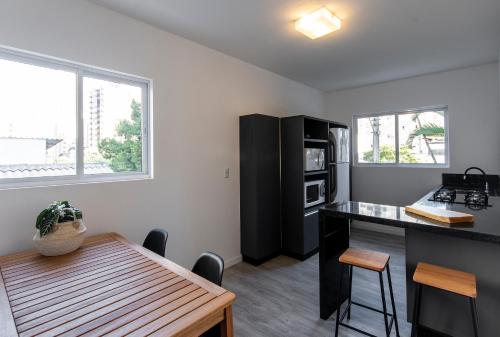 a kitchen with a table and a black refrigerator at Hotel Melo in Balneário Camboriú