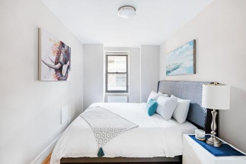 a white bedroom with a bed and a lamp at Gorgeous 2 BR in NYC with Elevator in New York