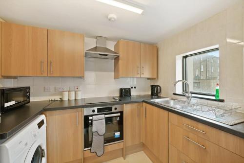 a kitchen with wooden cabinets and a washer and sink at City Centre, Free Wifi & Netflix in Kent