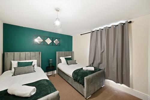 a bedroom with two beds and a green wall at City Centre, Free Wifi & Netflix in Kent