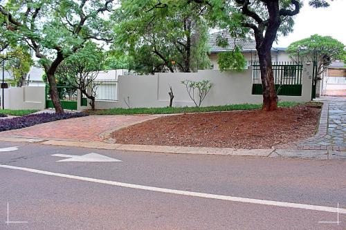an empty street with a white fence and trees at THE GLOBAL LINK HUB in Pretoria
