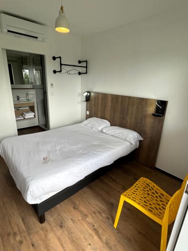 1 dormitorio con cama y taburete amarillo en The Originals Access, Hôtel Tulle (P'tit Dej-Hotel), en Tulle