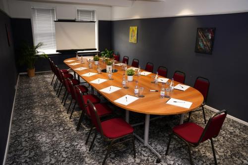 a conference room with a large wooden table and red chairs at Hamlet Hotels Maidstone in Maidstone