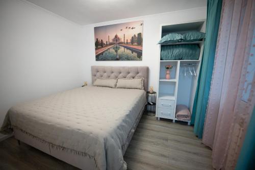 a bedroom with a bed and a painting on the wall at L&R Boutique Apartment in Oţelu Roşu