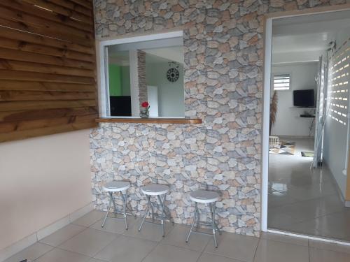 a stone wall with three stools and a mirror at BELLA in Gros-Morne