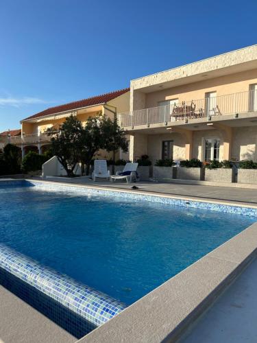 a swimming pool in front of a building at Apartments Jurić in Brodarica