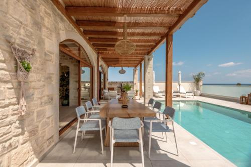 a dining room with a table and chairs and a pool at Pileas Villa, a Supreme Retreat by the Βeach, By ThinkVilla in Pigianos Kampos