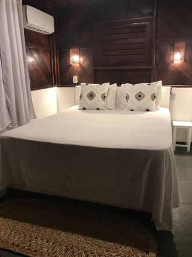 a large bed with white sheets and pillows at The Spot - Beachfront Sports Pousada in Icaraí
