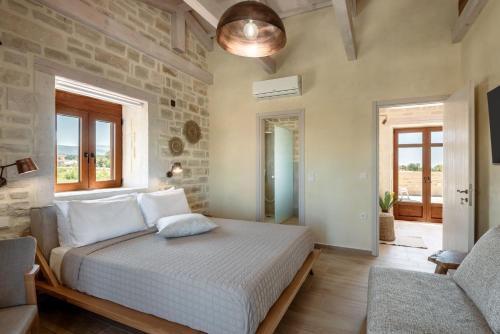 a bedroom with a large bed with a stone wall at Pileas Villa, a Supreme Retreat by the Βeach, By ThinkVilla in Pigianos Kampos