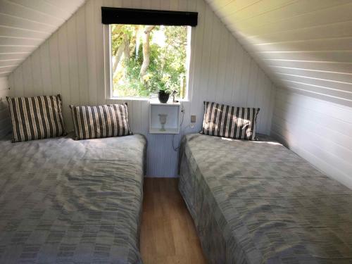 two beds in a small room with a window at Lovely Holiday Home Close To The Beach And Nature in Rødby