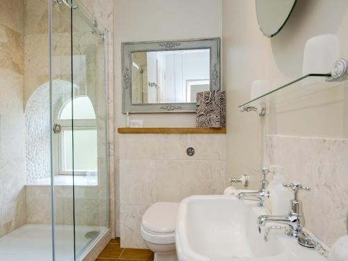 a bathroom with a sink and a toilet and a mirror at Penny Cottage in Bonsall