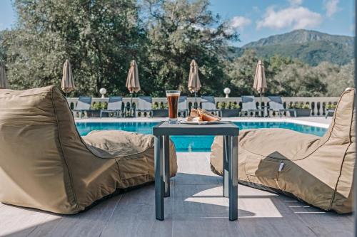 a table and chairs next to a pool at Pelithea Aparthotel in Corfu